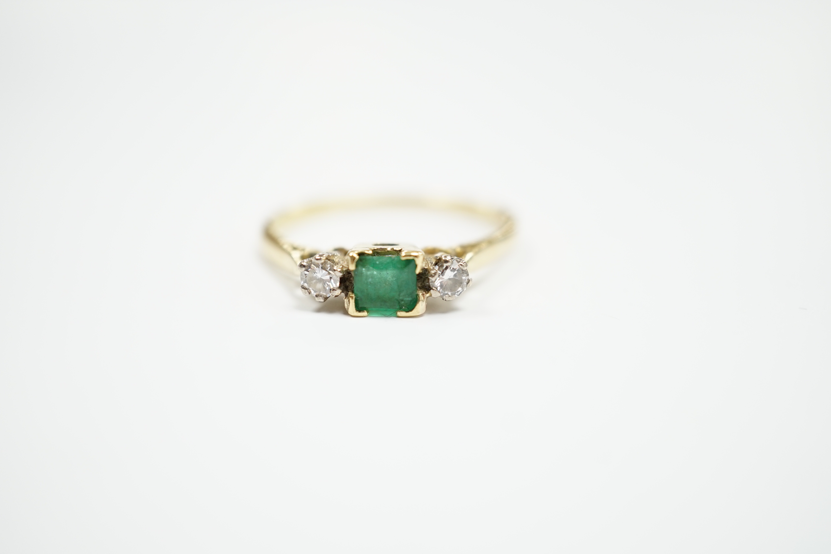 An 18ct and plat, single stone emerald and two stone diamond set ring, size Q/R, gross weight 2.6 grams.